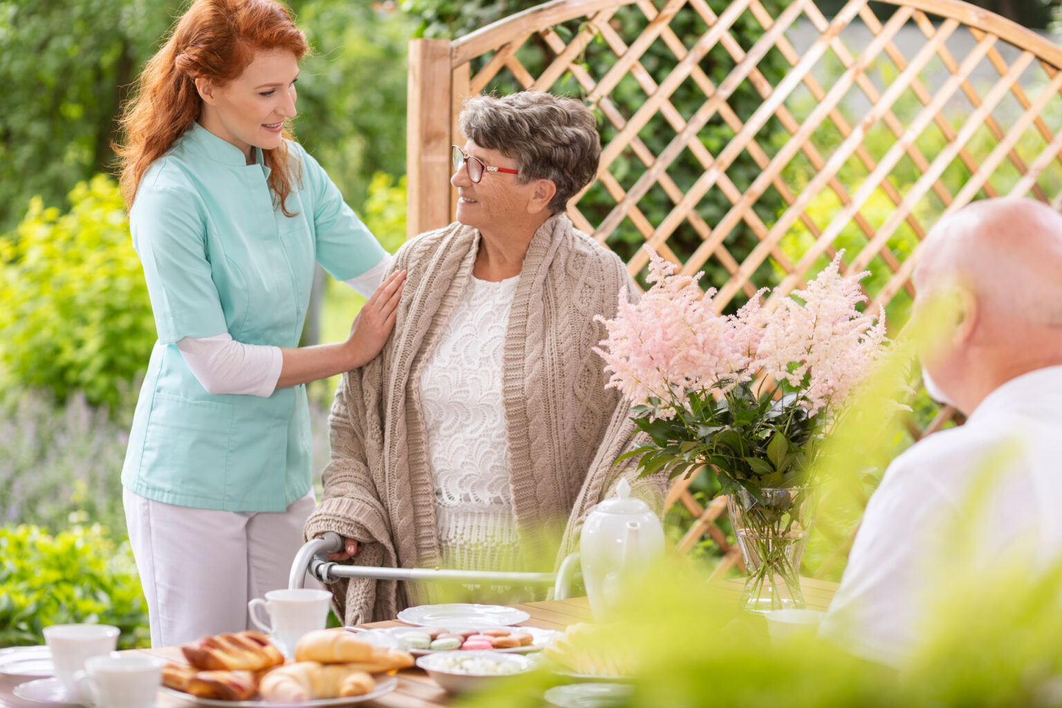 A,Tender,Caretaker,Assisting,An,Elderly,Woman,With,A,Walker